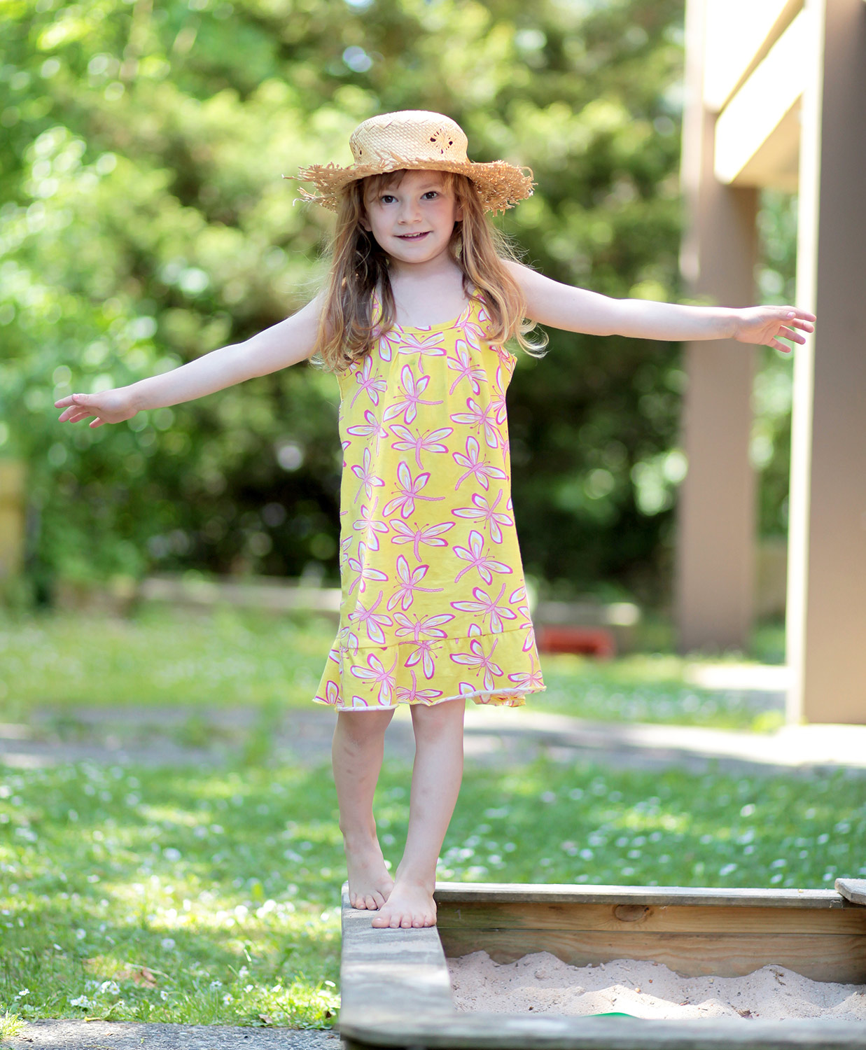 Mädchen balaciert auf einem Sandkastenrand