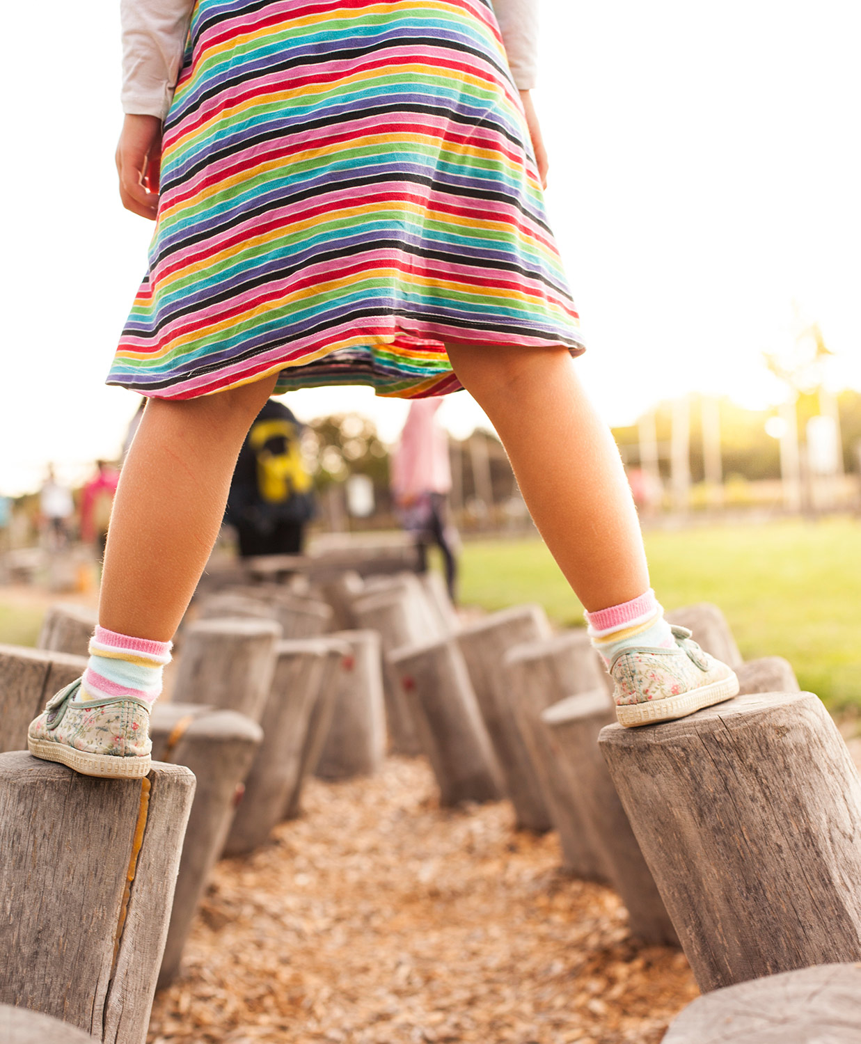 Mädchen geht auf Holzstämme die auseinanderliegen