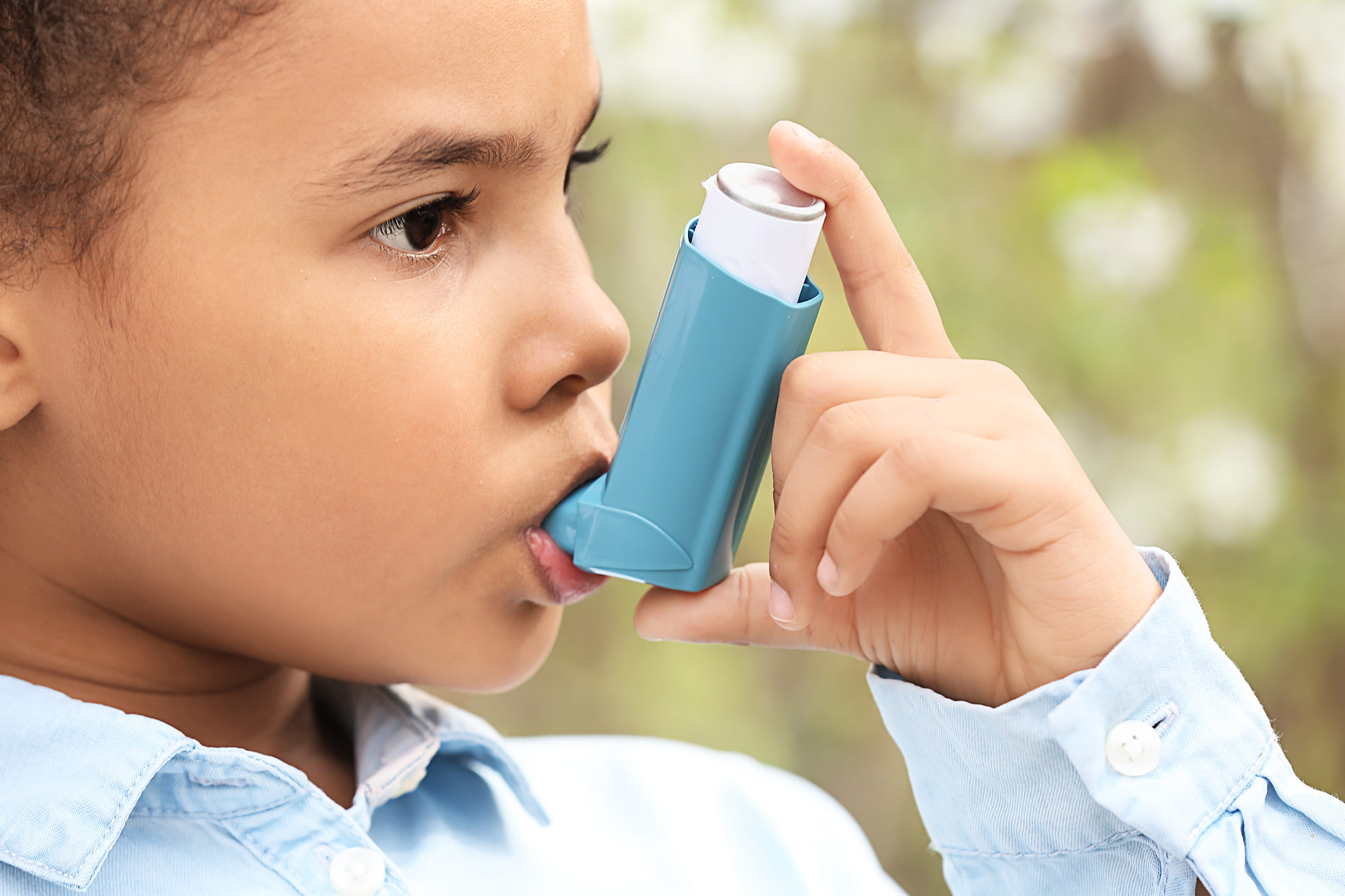 Kind hält sich ein Asthmaspray zum inhalieren in den Mund